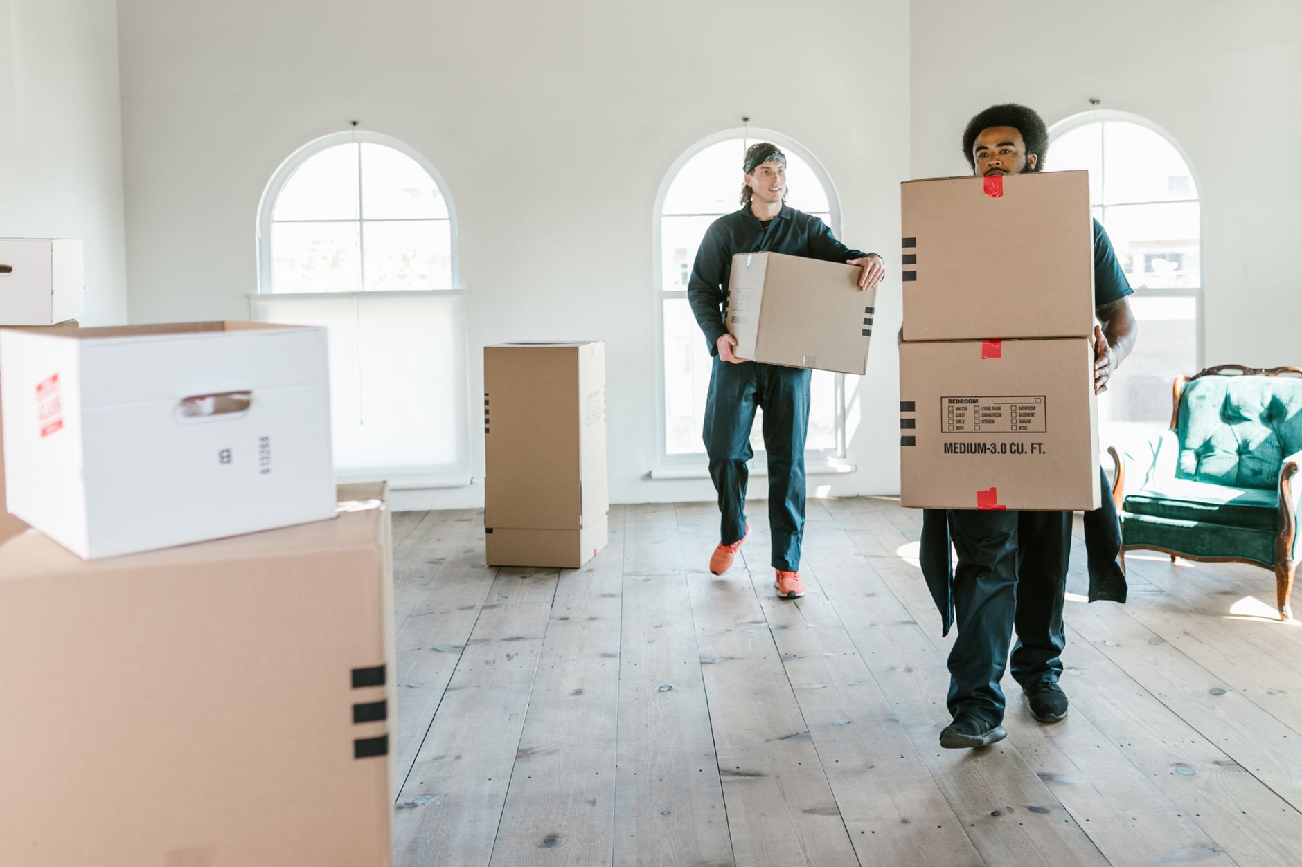 Dos operarios cargando cajas rotuladas en una vivienda luminosa