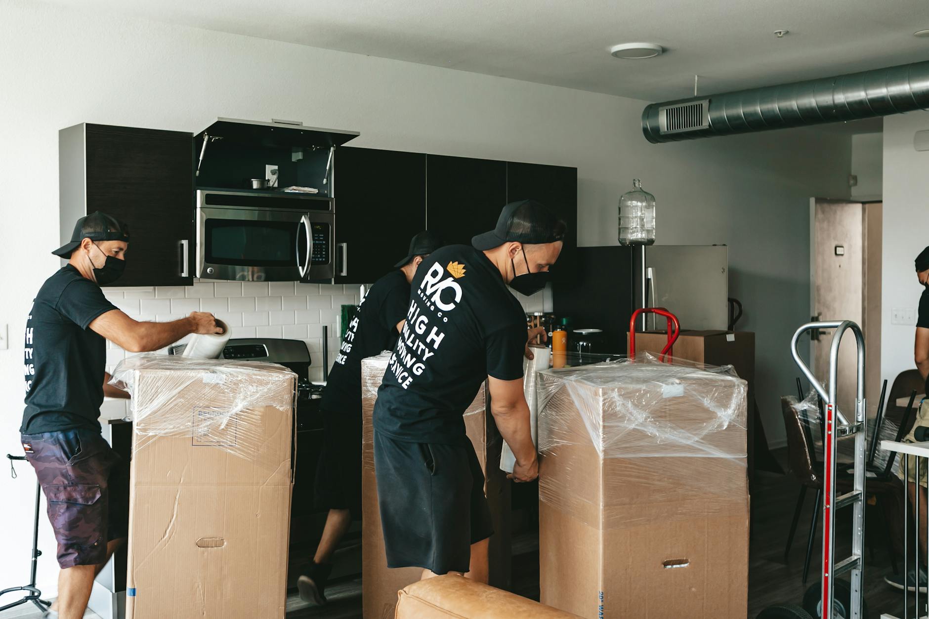 Equipo de Roble envolviendo cajas con film en una cocina